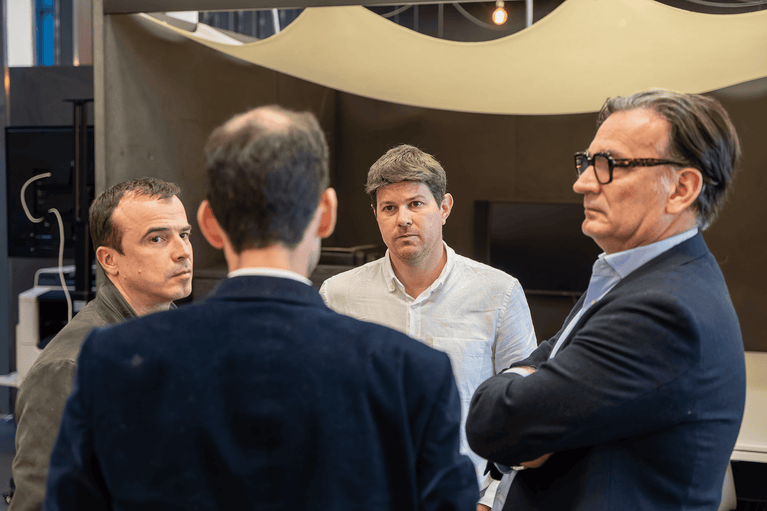 Un groupe de quatre professionnels échangeant lors d'un événement d'entreprise en intérieur - Fond'Actions des Possibles